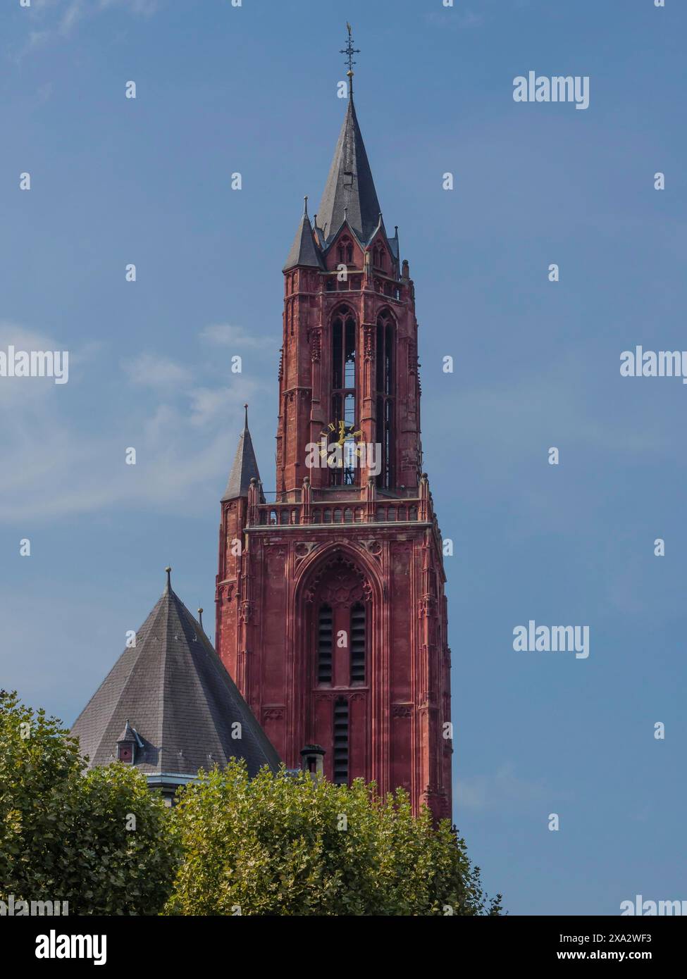 Une tour gothique de couleur rouge s'élève dans un ciel bleu clair, faisant partie d'une église historique, Maastricht, pays-Bas Banque D'Images