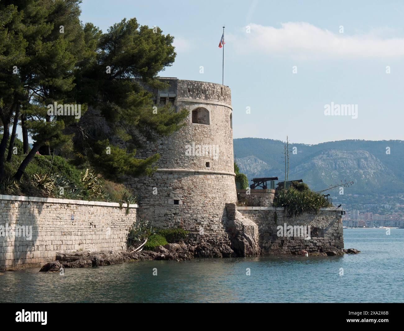 Forteresse historique en bord de mer, avec murs de pierre et drapeau, entourée de collines boisées, la seyne sur mer, france Banque D'Images