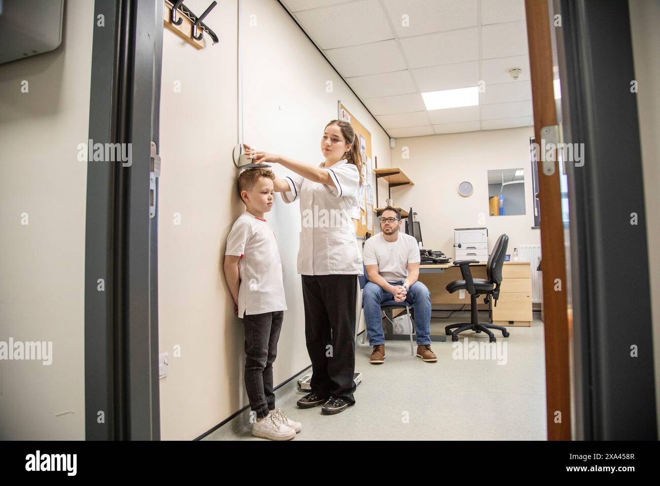 Professionnel de la santé mesurant la taille d'un enfant Banque D'Images