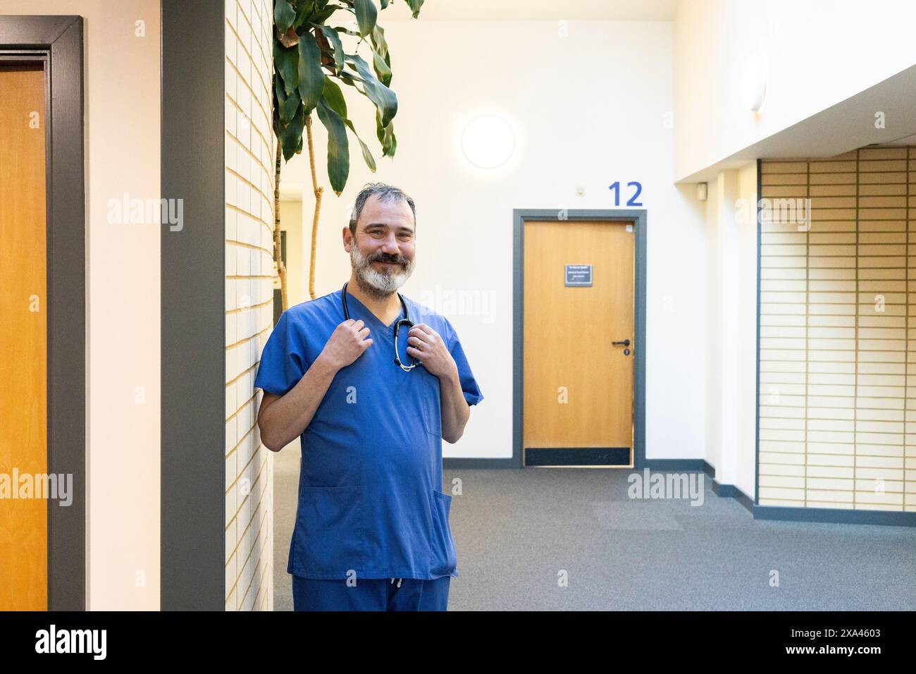 Homme en gommage bleu souriant dans un couloir d'un cabinet médical Banque D'Images