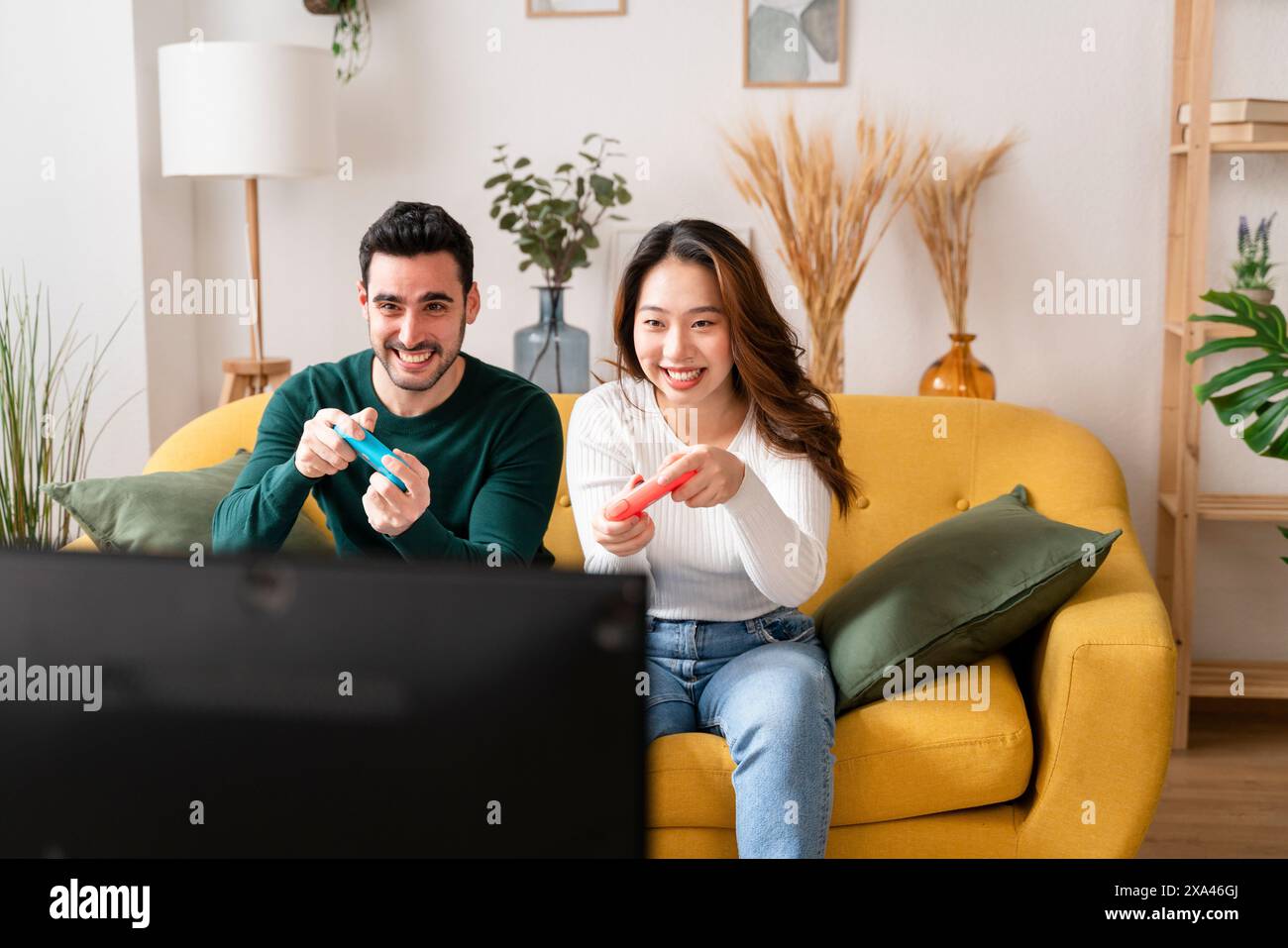 Deux personnes jouant à des jeux vidéo sur un canapé. Banque D'Images