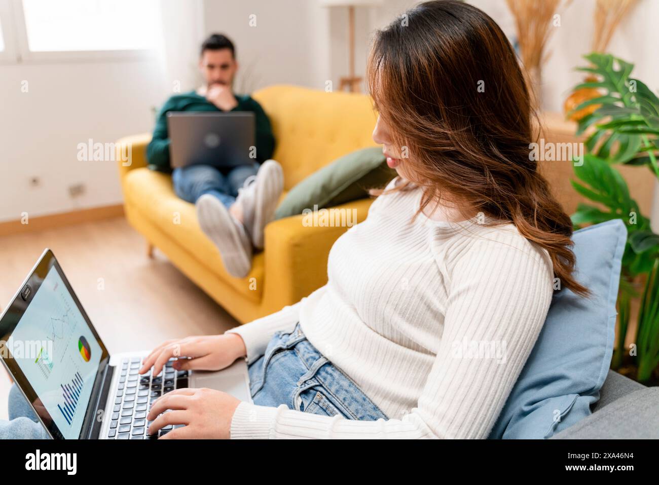 Femme travaillant sur ordinateur portable avec l'homme en arrière-plan Banque D'Images