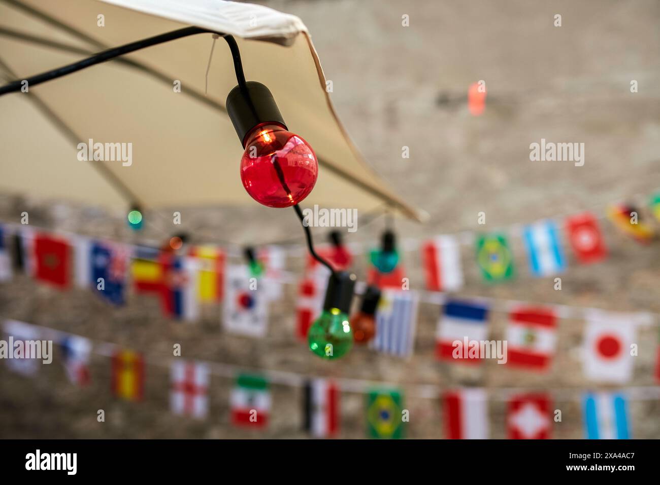 Les ampoules colorées sont enfilées devant un fond flou orné de petits drapeaux internationaux accrochés à un cordon. Banque D'Images