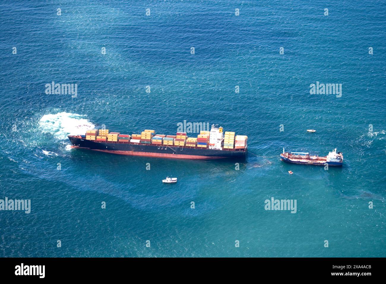 Une vue aérienne d'un grand cargo en difficulté en mer, accompagné de plusieurs petits navires, Nouvelle-Zélande Banque D'Images