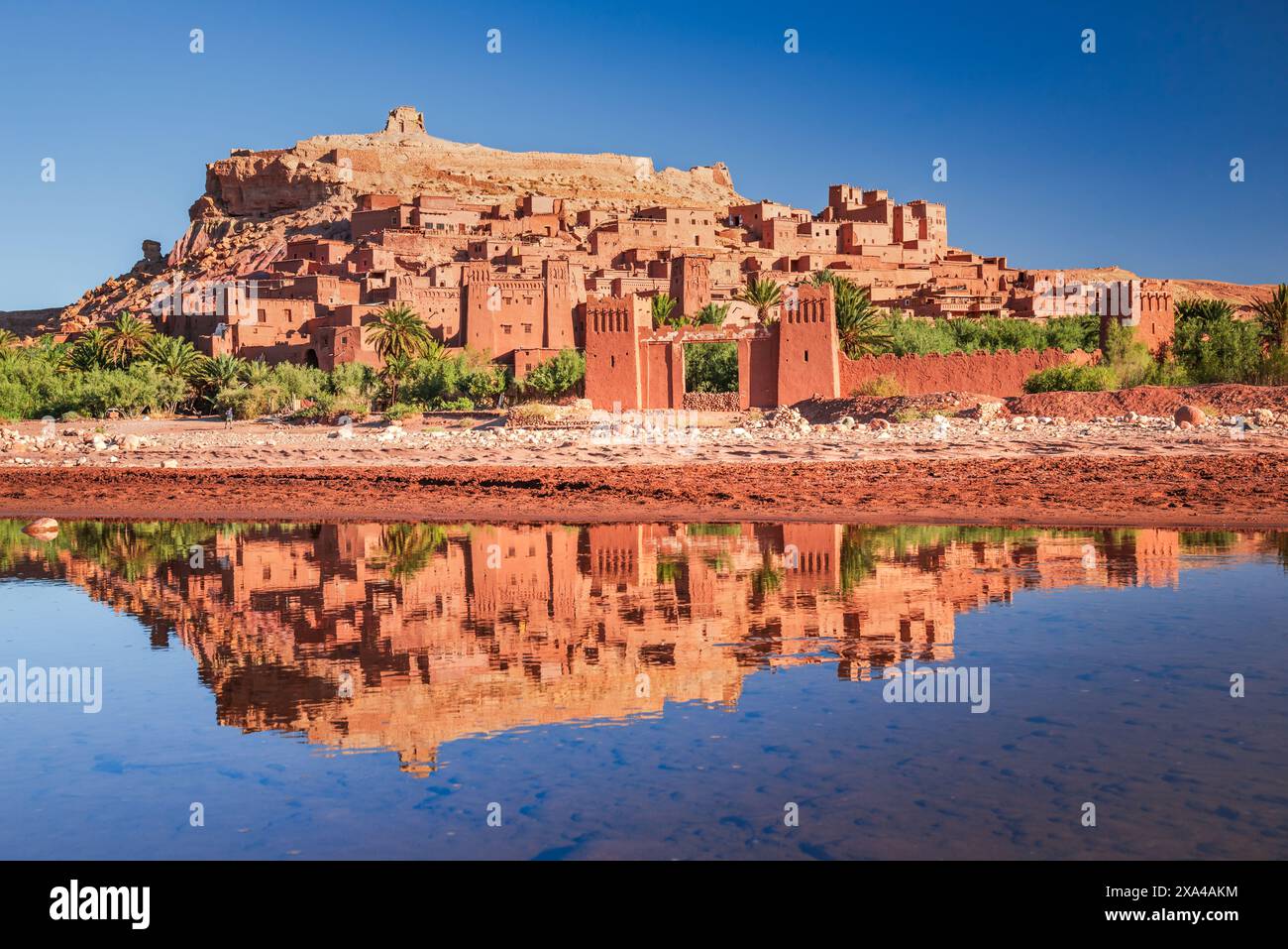 Ait-Benhaddou, Maroc. Célèbre exemple d'architecture en argile, ksar kasbah en Afrique du Nord, montagnes de l'Atlas. Réflexion de l'eau au lever du soleil. Banque D'Images