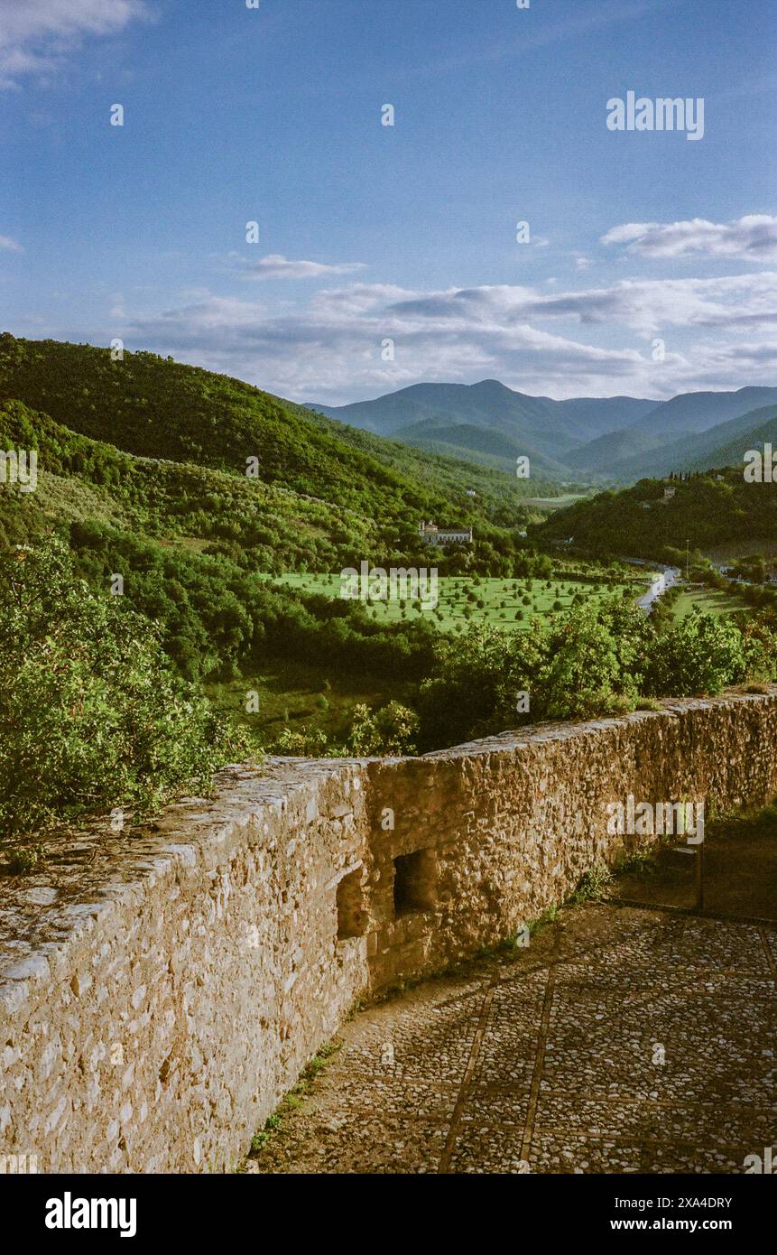 Une vue panoramique sur les collines verdoyantes sous un ciel bleu avec des nuages, prise d'un sentier aux murs de pierre menant au paysage. Banque D'Images