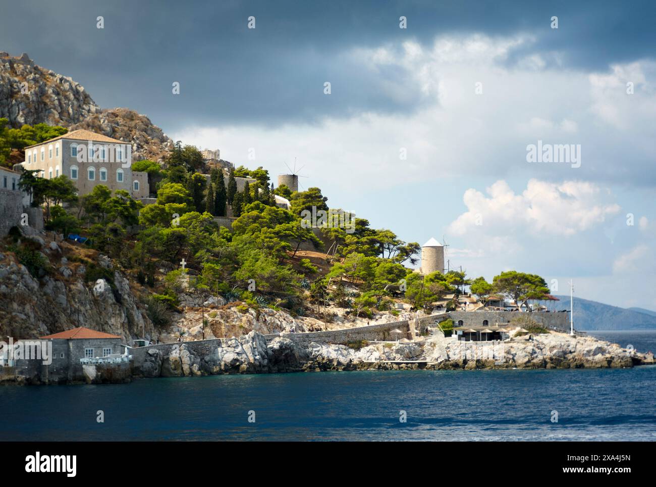 Une vue panoramique sur la côte avec une falaise accidentée ornée de bâtiments de style méditerranéen et une végétation luxuriante sous un ciel spectaculaire. Banque D'Images