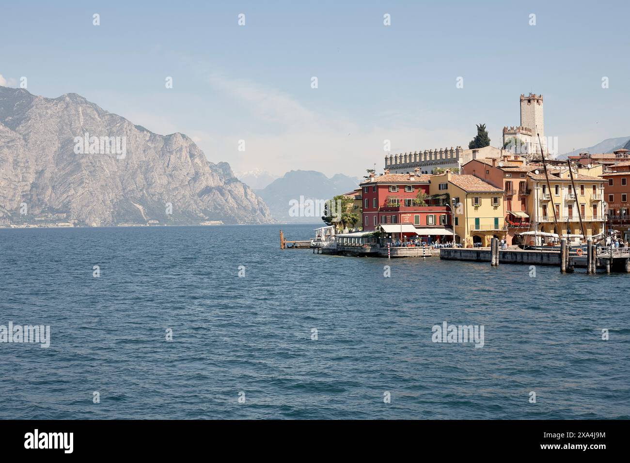 Une vue sereine sur une ville pittoresque au bord du lac avec des bâtiments colorés sur un fond de montagnes imposantes et un ciel bleu clair. Banque D'Images