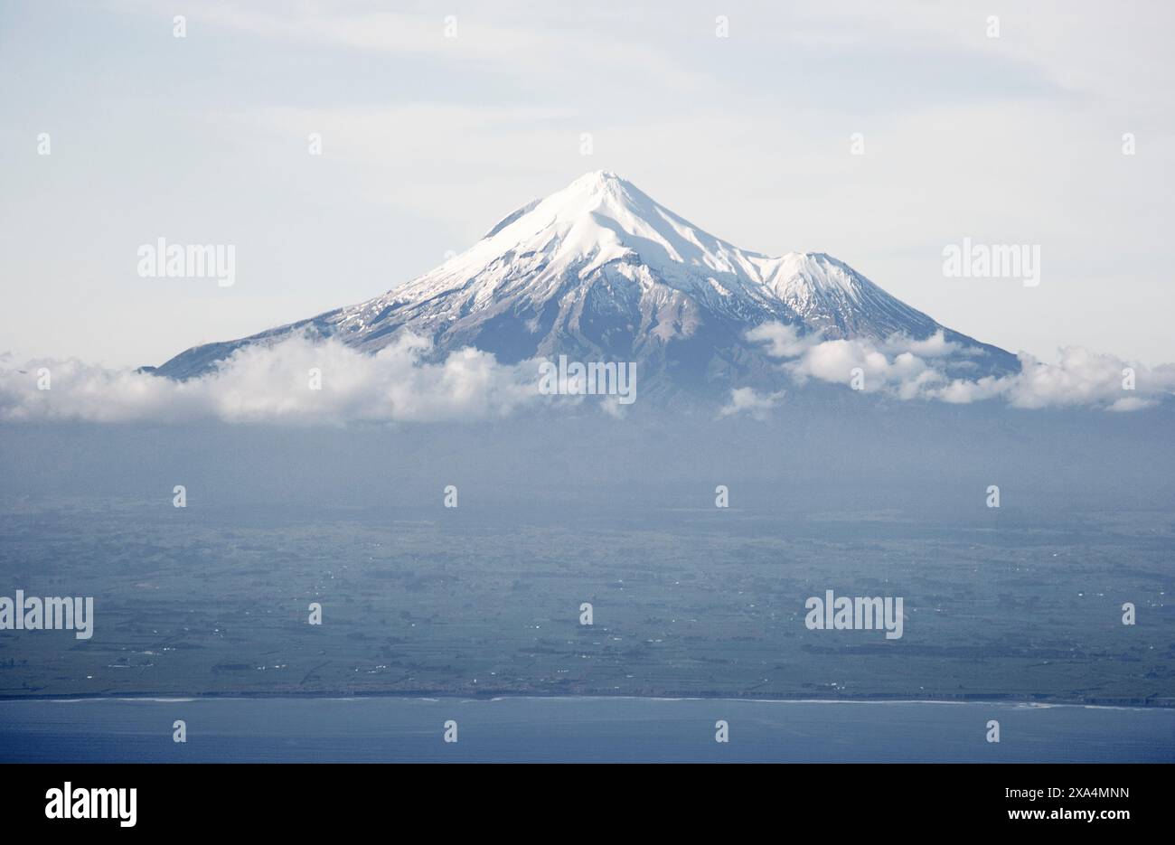 Sommet de montagne enneigé s'élevant au-dessus des nuages, avec une vue dégagée sur le sommet et un soupçon de paysage environnant en contrebas, Mt. Taranaki, Nouvelle-Zélande Banque D'Images