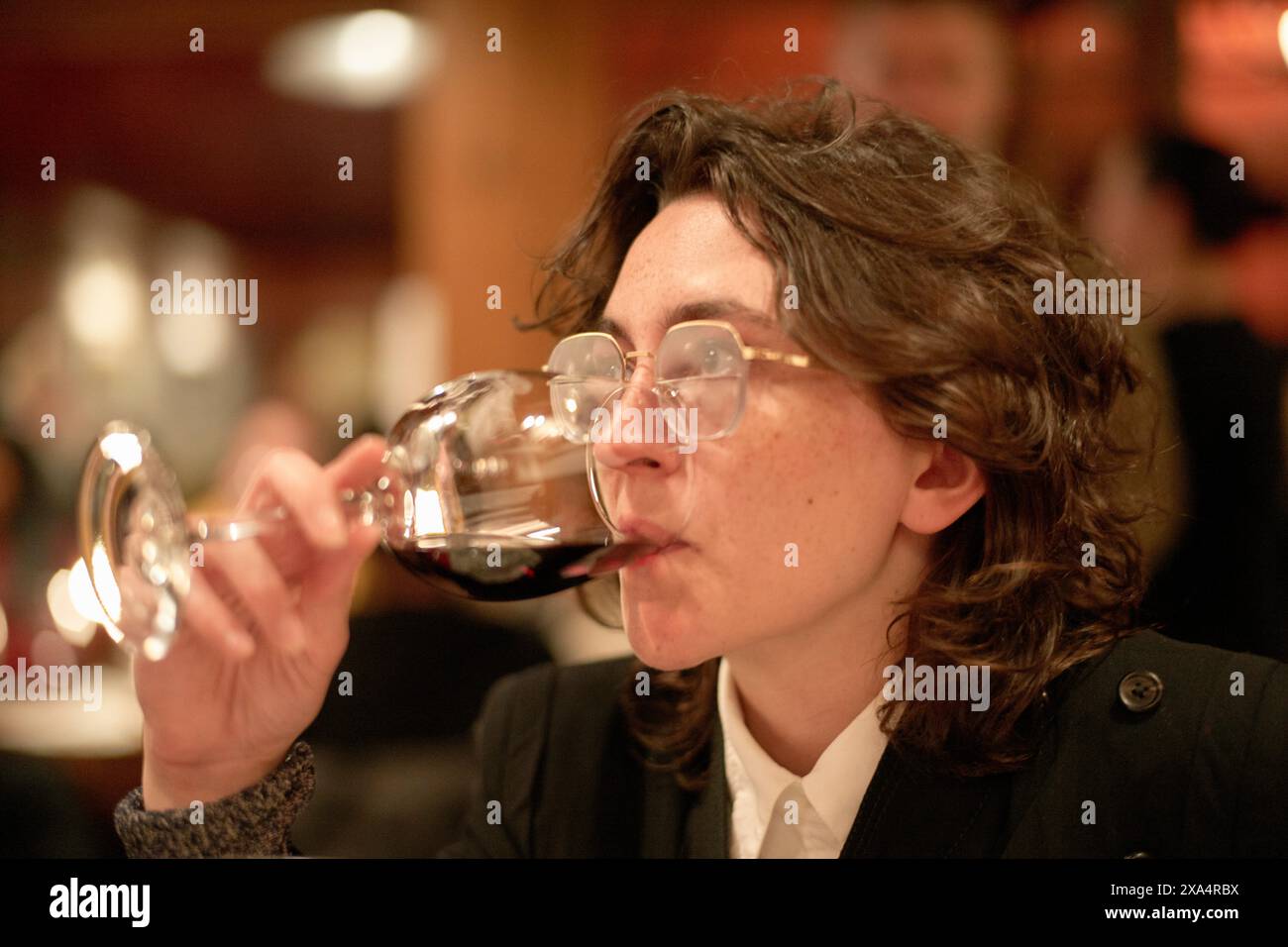 Femme dégustant du vin rouge dans un cadre de restaurant cosy Banque D'Images