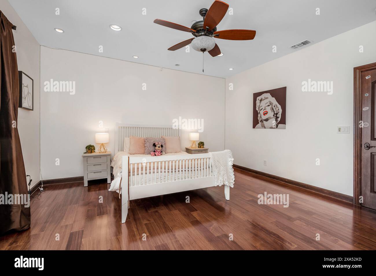 Lit dans la chambre avec parquet et ventilateur de plafond Banque D'Images
