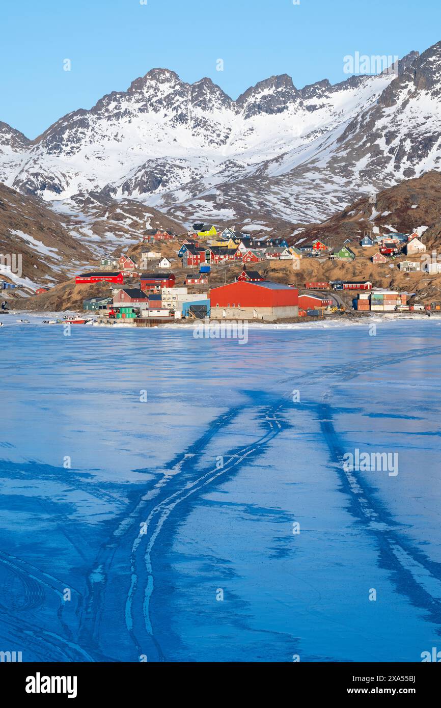 Sud-est du Groenland, région d'Ammassalik. Maisons colorées typiques dans la communauté isolée de Tasiilaq. Vue panoramique sur la glace rapide au printemps. Éditorial uniquement. Banque D'Images