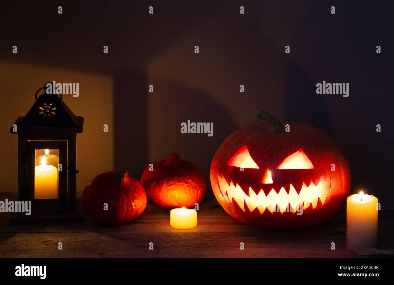 Lanterne jack à tête de citrouille d'Halloween avec des bougies allumées sur la vieille table en bois. Motif Halloween avec citrouilles. Banque D'Images