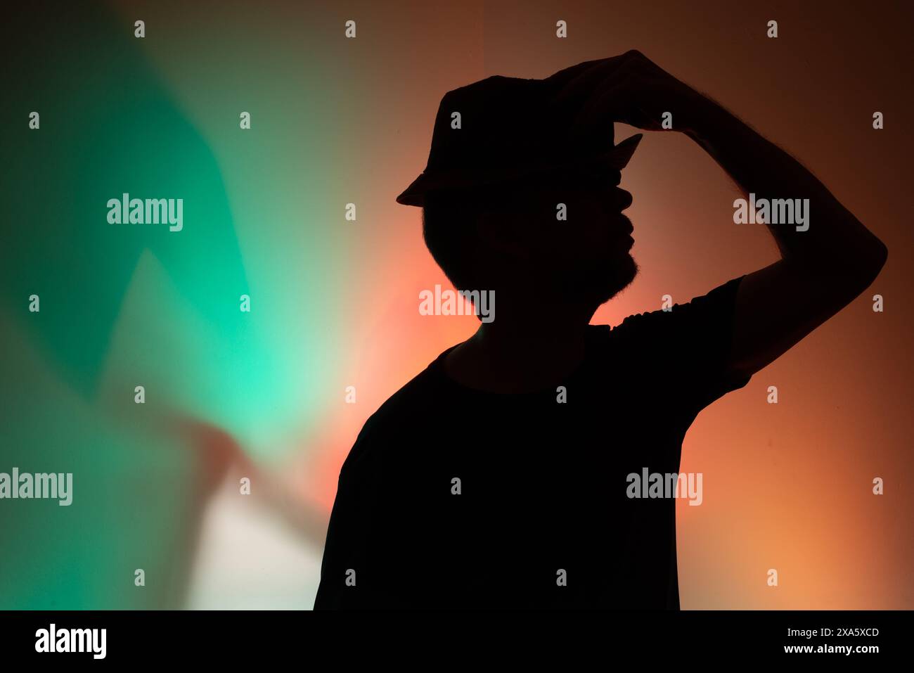 Portrait studio d'un homme tenant un chapeau en silhouette. Isolé sur fond coloré. Banque D'Images