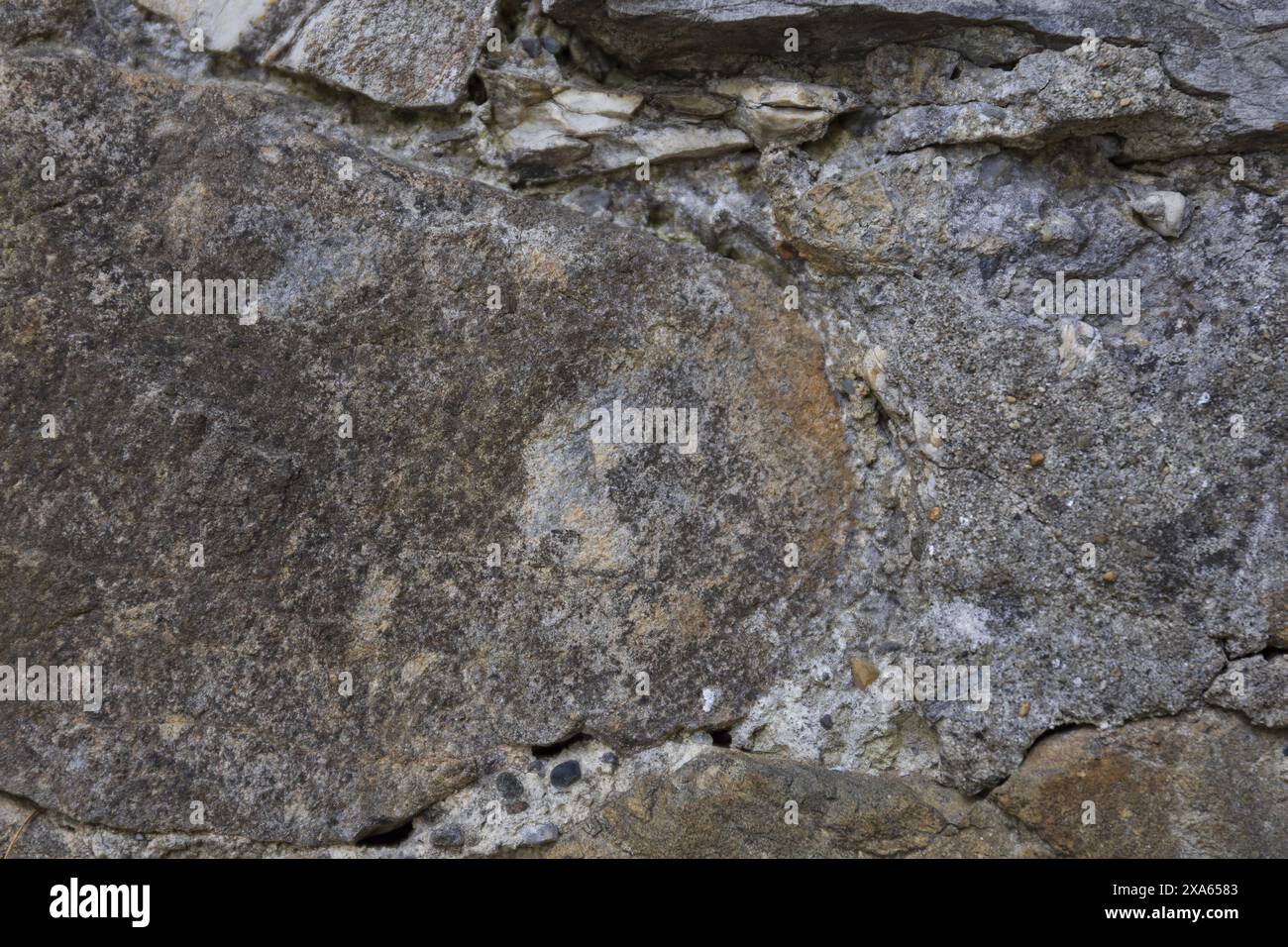 photo en gros plan d'une surface murale texturée en pierre gris foncé présentant des fissures et des éclats Banque D'Images