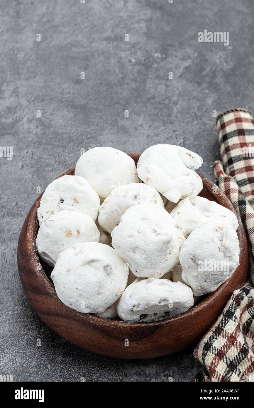 Mini meringues traditionnelles avec des noix dans un bol en bois sur fond gris Banque D'Images