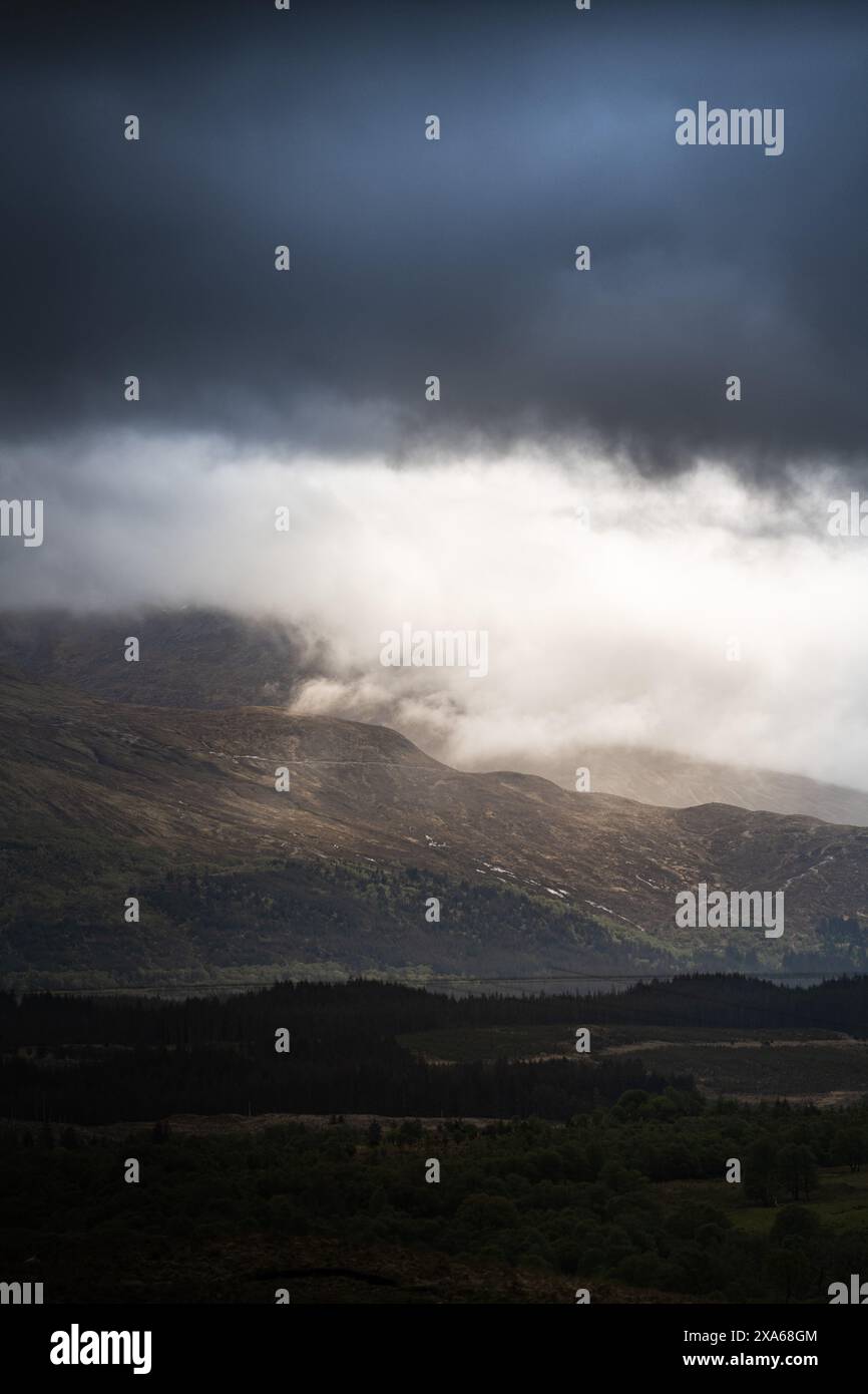 Des nuages sombres planent au-dessus de montagnes lointaines Banque D'Images