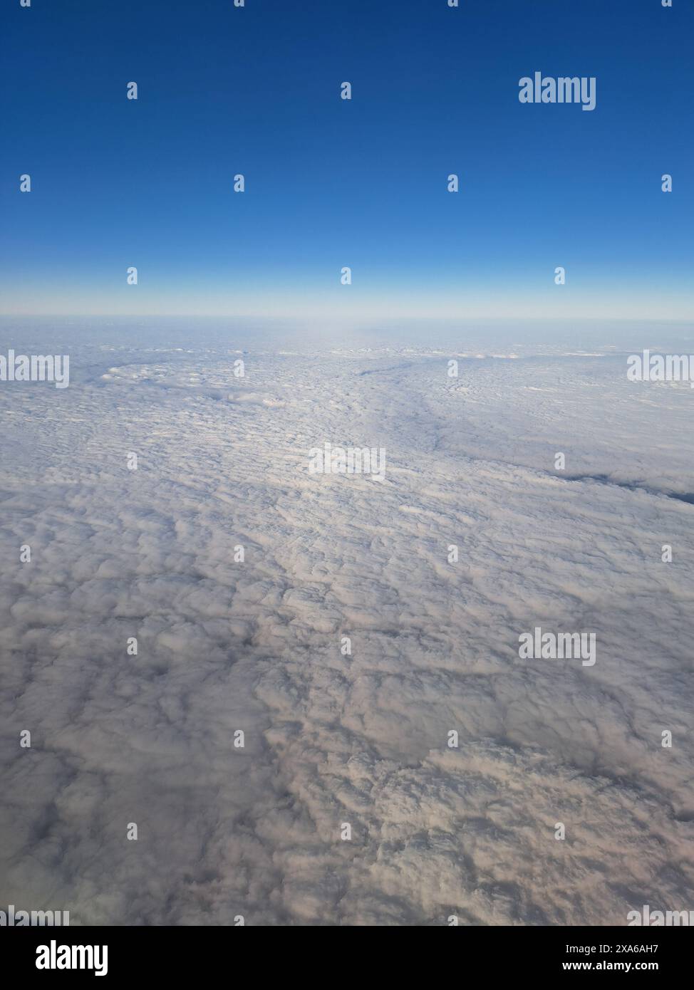 Un avion volant à travers des nuages moelleux contre un ciel bleu clair Banque D'Images