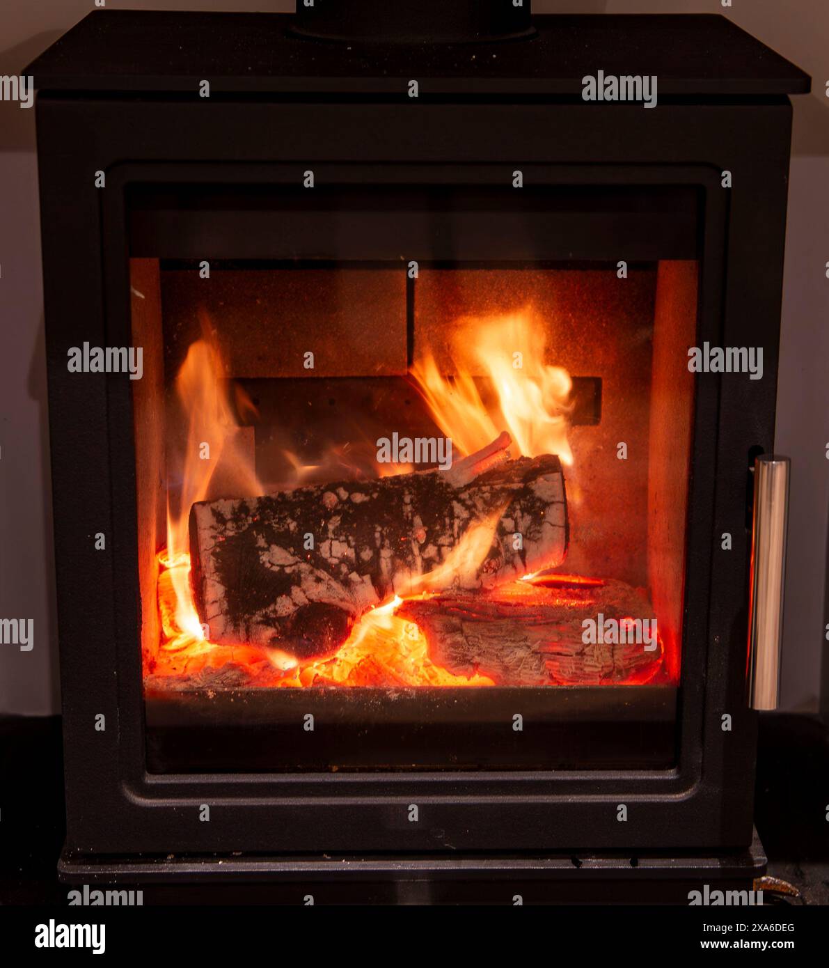 Vue d'une bûche en feu dans un poêle à bois fermé avec des flammes vibrantes et des braises incandescentes Banque D'Images