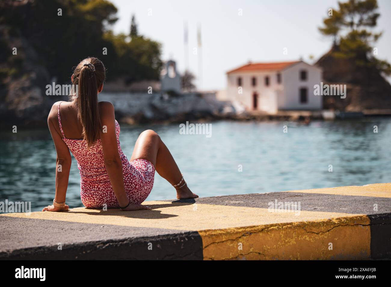 Femme dans une robe courte assise sur un quai Banque D'Images