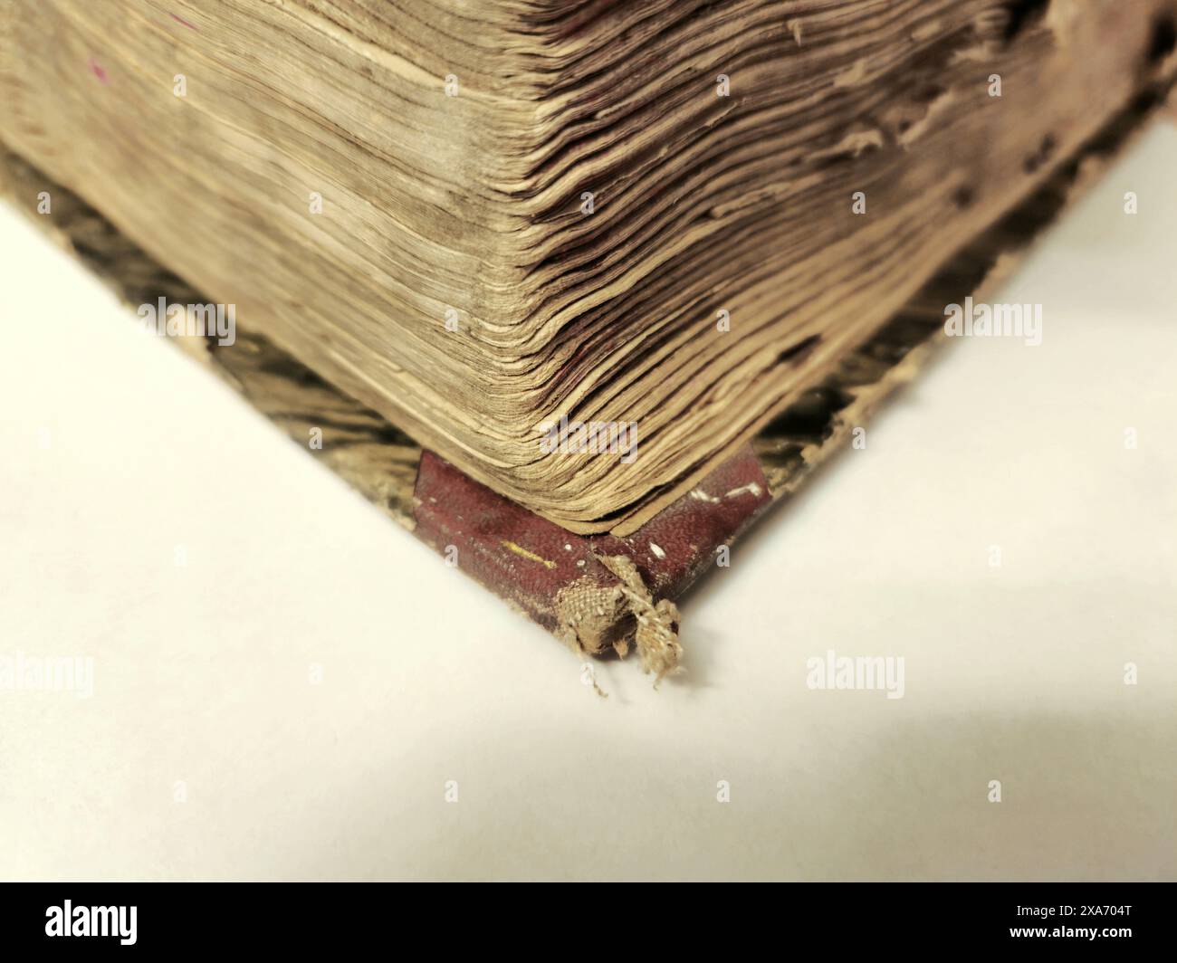 Gros plan d'un vieux coin de livre usé, montrant des pages vieilles et effilochées et une couverture en lambeaux. Banque D'Images