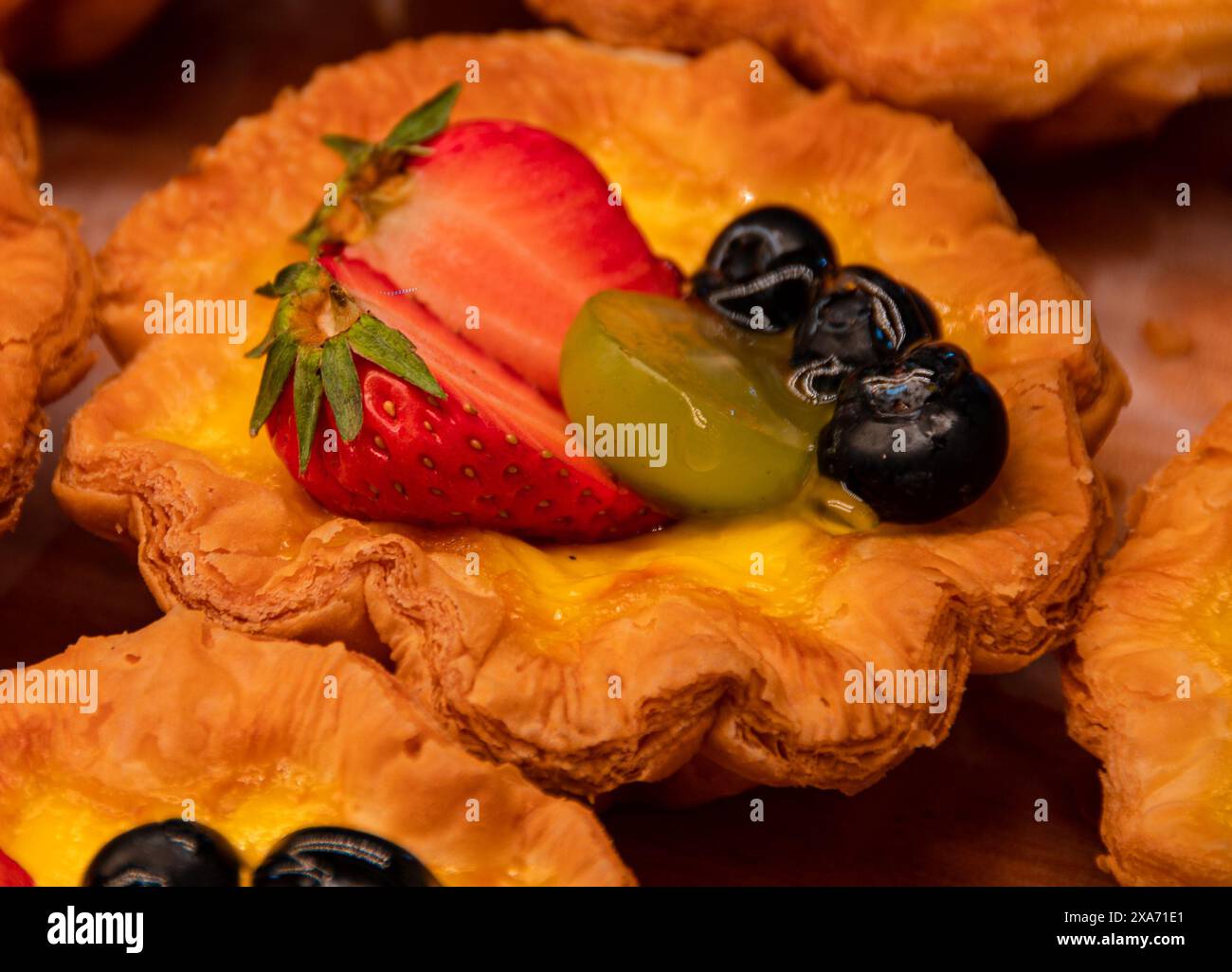 Gâteaux aux fruits assortis affichés sur un comptoir de cuisine avec des fruits frais Banque D'Images
