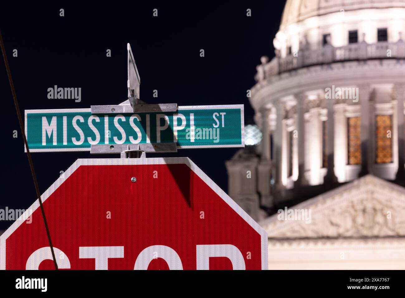 Jackson, Mississippi, États-Unis - 23 avril 2024 : une lumière de nuit artificielle brille sur le panneau de Mississippi Street et le capitole de l'État. Banque D'Images