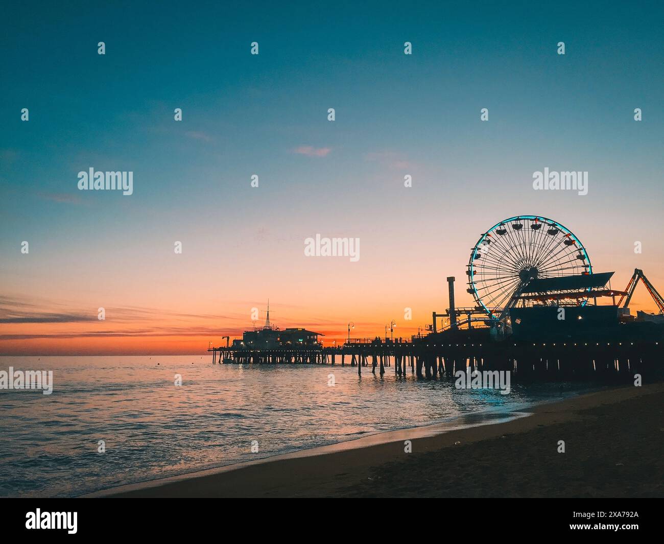 Coucher de soleil derrière la grande roue sur la plage avec la jetée en arrière-plan Banque D'Images