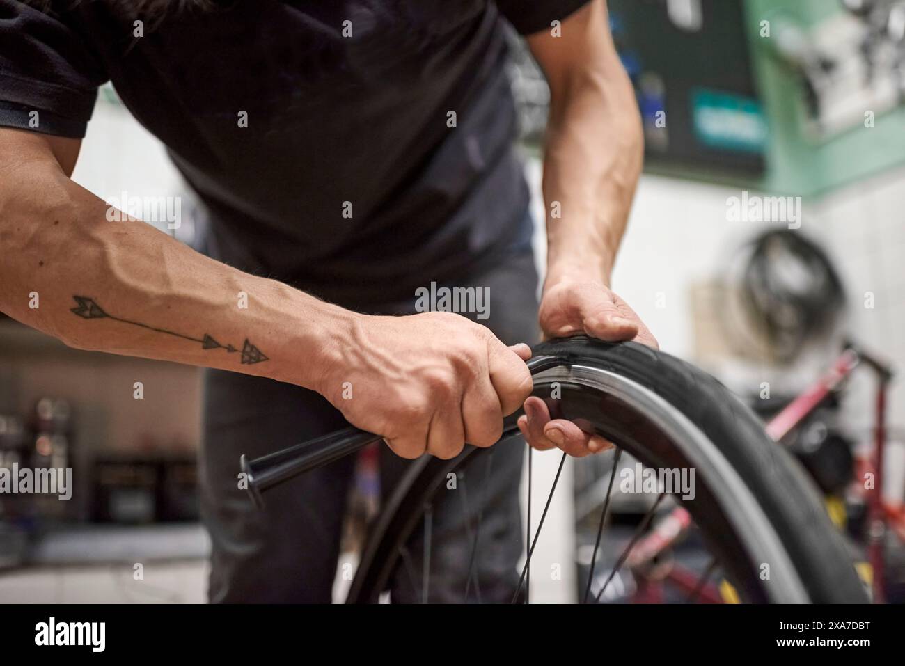 Réparateur de vélos inconnu installant un pneu plein airless sur une roue de vélo dans un atelier de réparation. Composition de mise au point sélective avec espace de copie. Banque D'Images