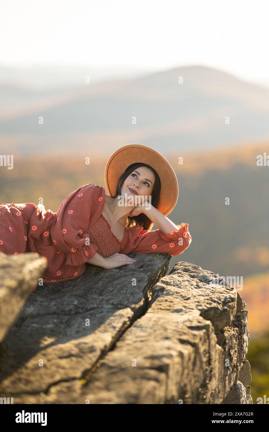 Une femme dans un chapeau de soleil se prélasse sur un bord de rocher Banque D'Images