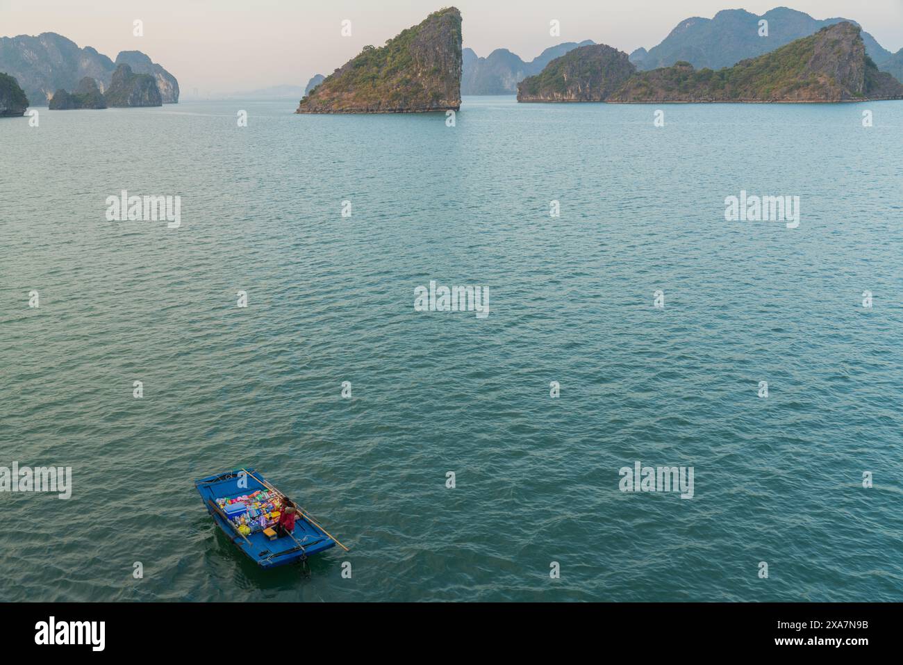 Un petit bateau flottant sur un vaste plan d'eau avec des montagnes au loin Banque D'Images