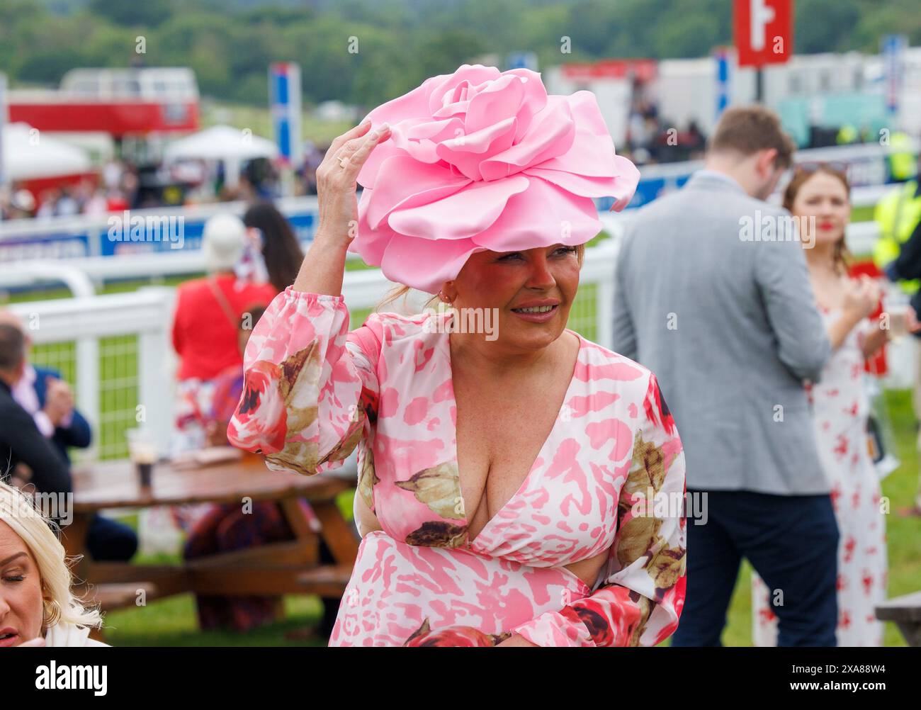Une femme tient son chapeau dans des conditions blustery au festival Epsom Derby. Derby Day à Epsom, l'une des plus grandes courses du monde. Banque D'Images