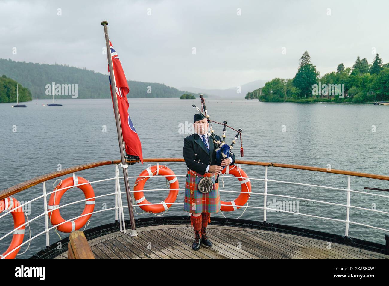 Richard Cowie, joueur solitaire des francs-maçons de Cumbria, joue sur le pont de l'un des bateaux à vapeur traditionnels Windermere Lake Cruises à Bowness-on-Windermere, Lake District, lors d'un événement commémoratif du débarquement. Le Piper a joué à divers endroits autour de la Cumbrie du Sud au cours des 8 derniers jours, pour honorer le Piper Bill Millin du jour J qui a joué sur les plages de Normandie le jour J pour confondre les troupes ennemies et remonter le moral des troupes alliées. Date de la photo : mercredi 5 juin 2024. Banque D'Images