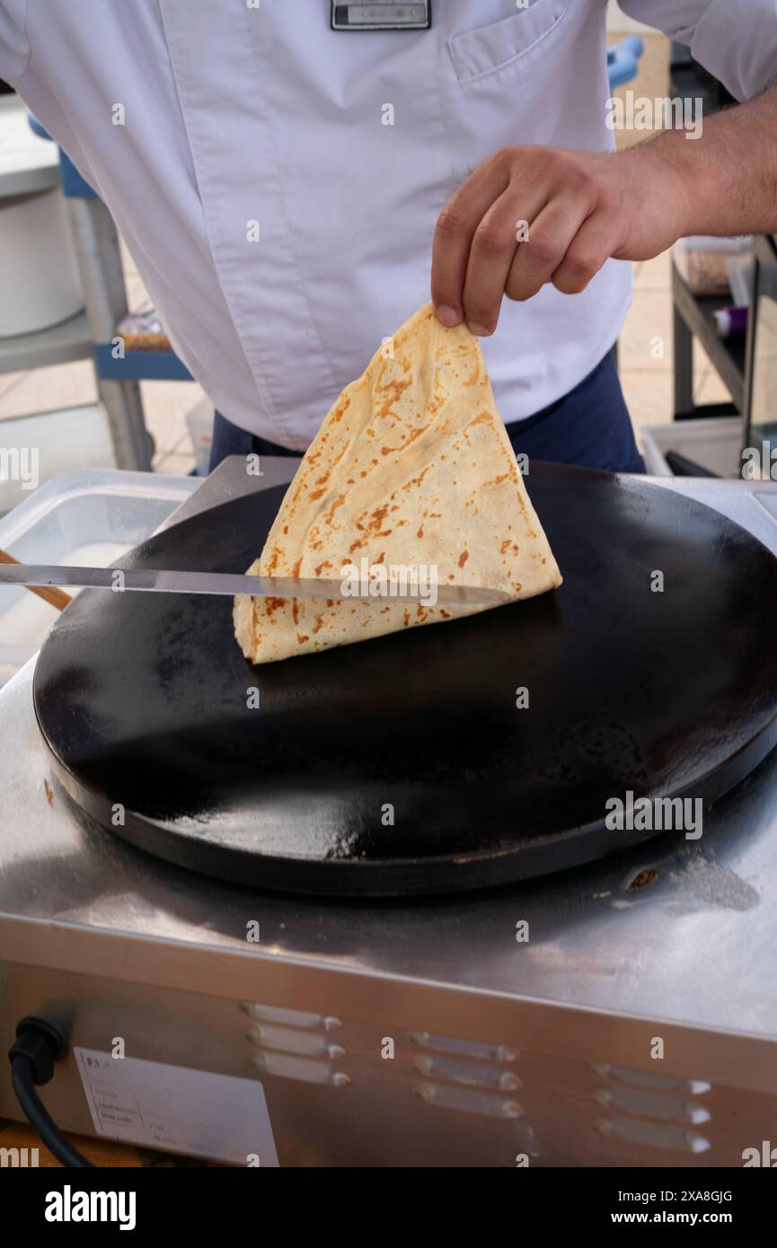 Un chef fait une tortilla sur une poêle. Le chef porte un tablier blanc et une chemise bleue Banque D'Images