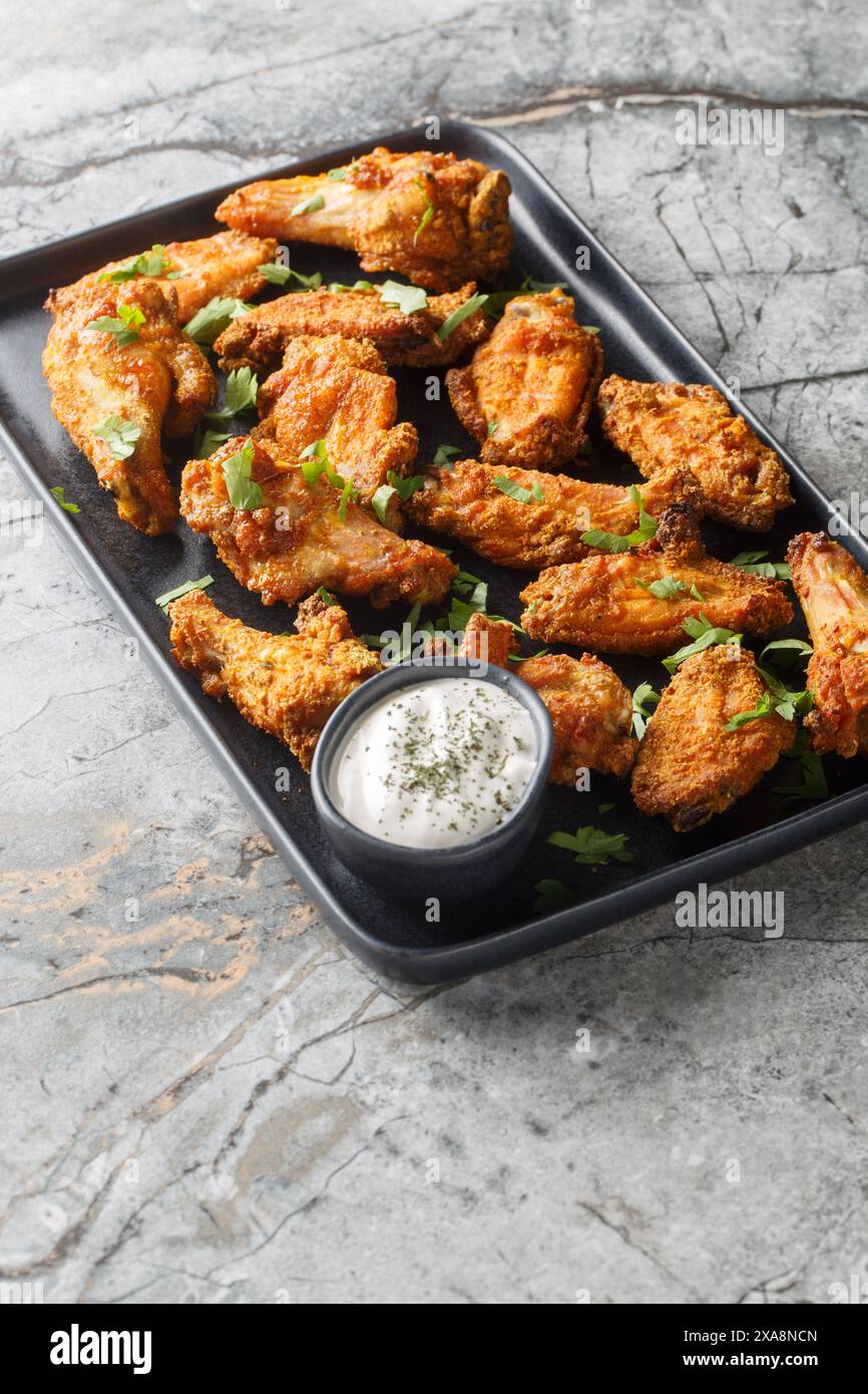 Ailes de poulet croustillantes panées au curry dans une assiette sur la table. Vertical Banque D'Images