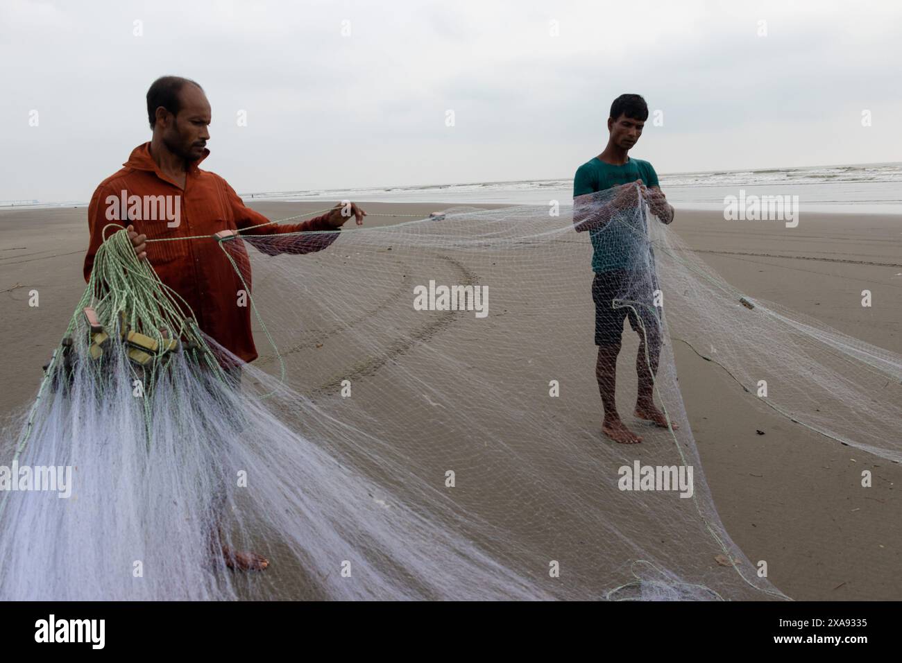 5 juin 2024, Cox's Bazar, Chittagong, Bangladesh : des pêcheurs préparent des filets de pêche pour attraper du poisson sur la plage de la mer de Cox's Bazar, Bangladesh. Le gagne-pain de la communauté des pêcheurs ici dépend largement de la pêche. Avec chaque nœud et ajustement, ils honorent une tradition intemporelle de subsistance qui s'harmonise avec les rythmes du monde naturel. Cox's Bazar, la plus longue plage marine naturelle du monde, s'étend sur plus de 120 kilomètres le long de la côte sud-est du Bangladesh. Réputée pour son sable doré, ses couchers de soleil vibrants et ses vagues, elle attire des millions de touristes chaque année. (Crédit image : © Joy Banque D'Images