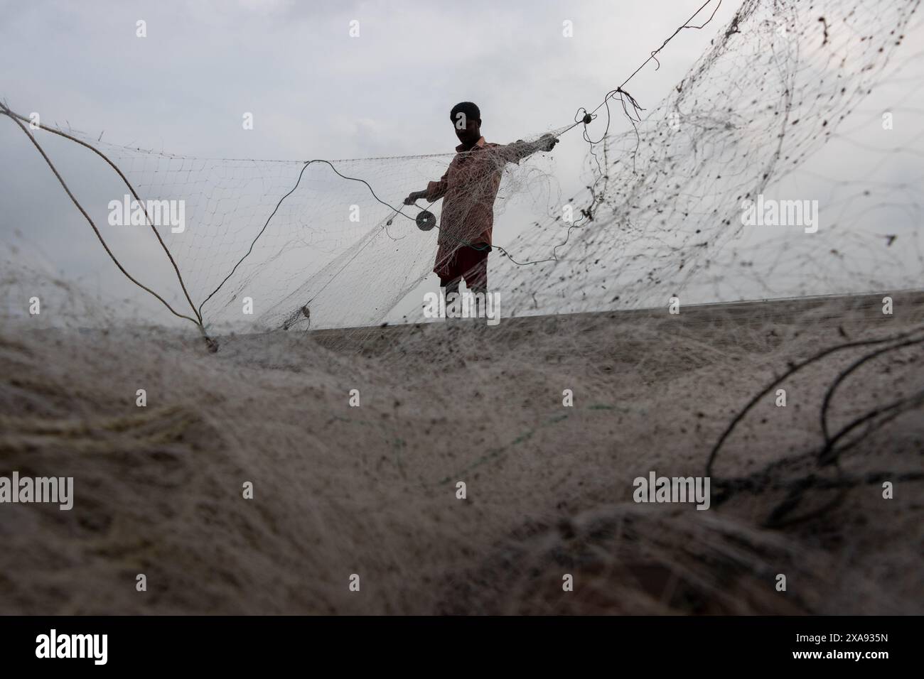 5 juin 2024, Cox's Bazar, Chittagong, Bangladesh : des pêcheurs préparent des filets de pêche pour attraper du poisson sur la plage de la mer de Cox's Bazar, Bangladesh. Le gagne-pain de la communauté des pêcheurs ici dépend largement de la pêche. Avec chaque nœud et ajustement, ils honorent une tradition intemporelle de subsistance qui s'harmonise avec les rythmes du monde naturel. Cox's Bazar, la plus longue plage marine naturelle du monde, s'étend sur plus de 120 kilomètres le long de la côte sud-est du Bangladesh. Réputée pour son sable doré, ses couchers de soleil vibrants et ses vagues, elle attire des millions de touristes chaque année. (Crédit image : © Joy Banque D'Images