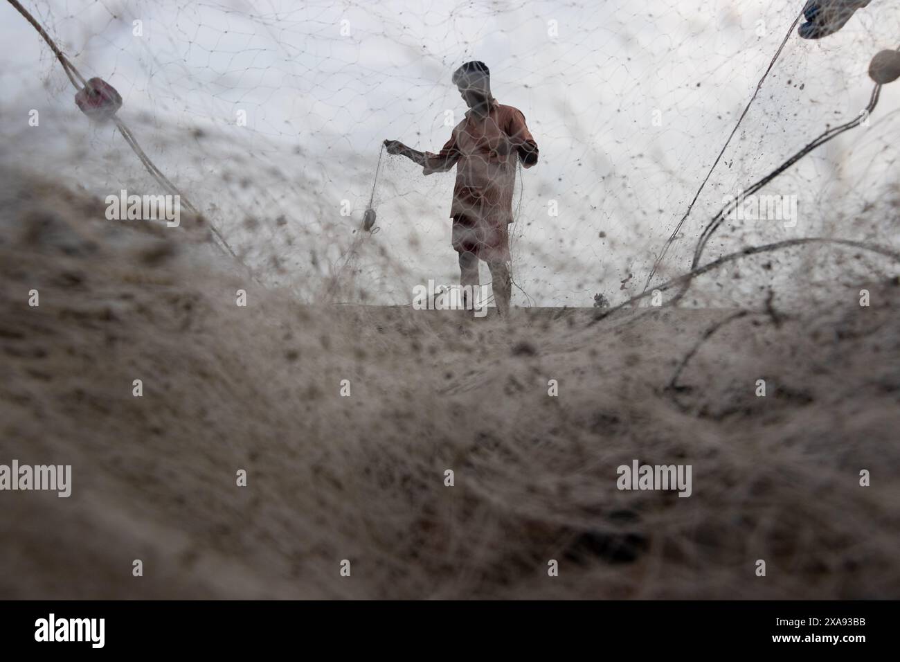 5 juin 2024, Cox's Bazar, Chittagong, Bangladesh : des pêcheurs préparent des filets de pêche pour attraper du poisson sur la plage de la mer de Cox's Bazar, Bangladesh. Le gagne-pain de la communauté des pêcheurs ici dépend largement de la pêche. Avec chaque nœud et ajustement, ils honorent une tradition intemporelle de subsistance qui s'harmonise avec les rythmes du monde naturel. Cox's Bazar, la plus longue plage marine naturelle du monde, s'étend sur plus de 120 kilomètres le long de la côte sud-est du Bangladesh. Réputée pour son sable doré, ses couchers de soleil vibrants et ses vagues, elle attire des millions de touristes chaque année. (Crédit image : © Joy Banque D'Images