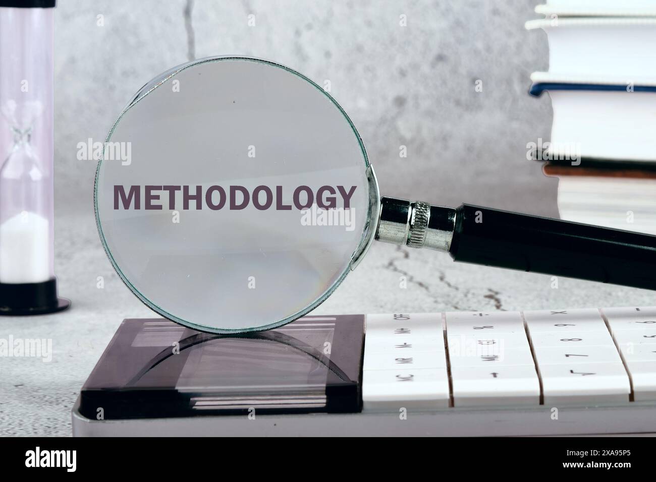 Concept d'étude ou d'activité. Le mot méthodologie écrit à travers une loupe sur un fond gris. Image en noir et blanc Banque D'Images