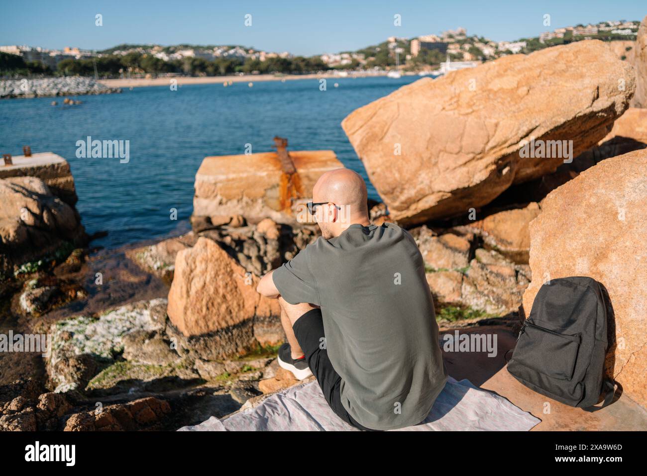 Homme et chien assis sur le rocher près de l'eau Banque D'Images