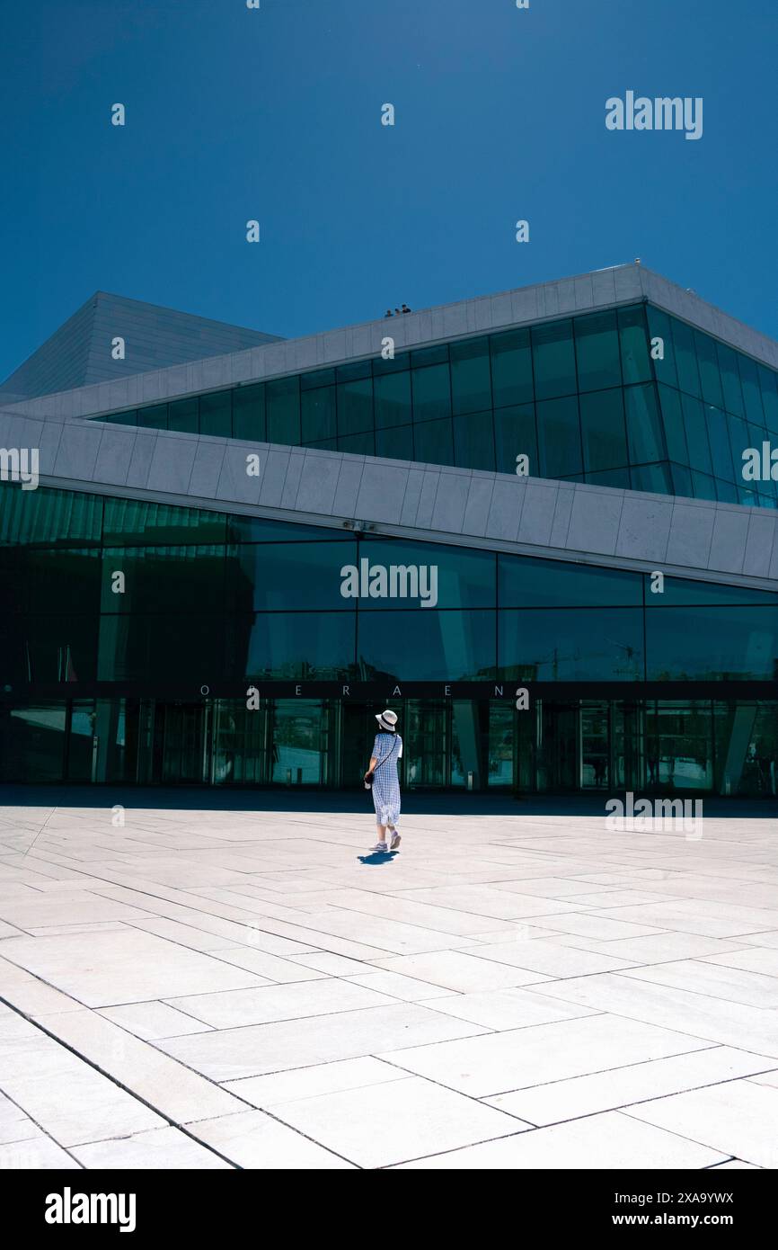 Une femme se promenant sur une passerelle carrelée devant un bâtiment Banque D'Images