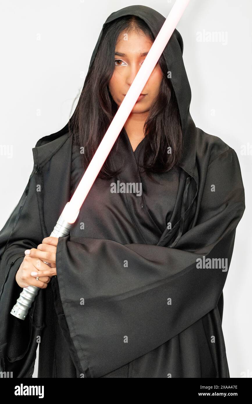 Un guerrier fantastique de science-fiction femme cosplayer dans une robe noire tenant un sabre sur un fond blanc Banque D'Images