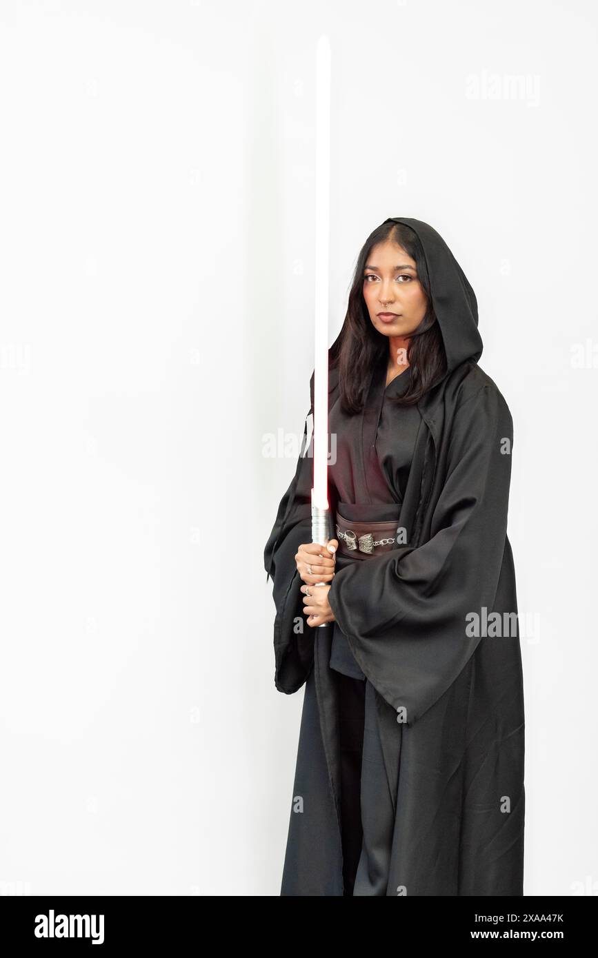 Un guerrier fantastique de science-fiction femme cosplayer dans une robe noire tenant un sabre sur un fond blanc Banque D'Images