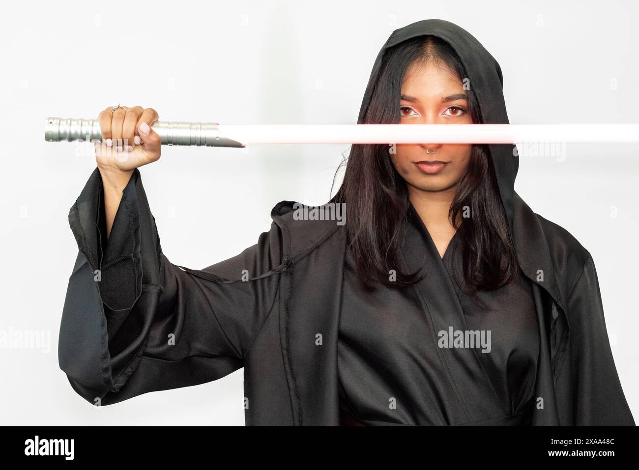 Un guerrier fantastique de science-fiction femme cosplayer dans une robe noire tenant un sabre sur un fond blanc Banque D'Images
