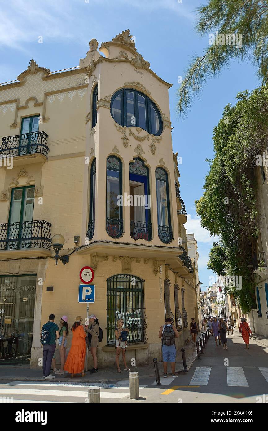 Sitges, Barcelone, Espagne-05 juin 2024 : coin animé avec un bâtiment jaune mis en valeur par son architecture unique et l'agitation du passé Banque D'Images
