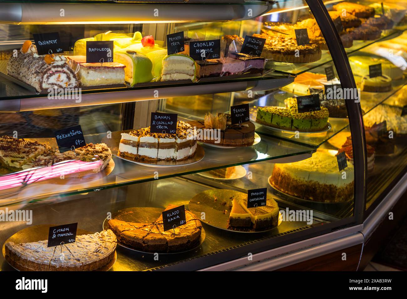 Des gâteaux et des pâtisseries étiquetés « Napoleon », « Choklad Mousse » et « Citron & Mandel » remplissent le comptoir incurvé du Café Linné à Uppsala. Svartbäcksgatan 22, Uppsala, Comté d'Uppsala, Suède. Banque D'Images