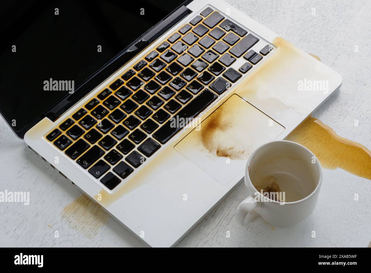 Café renversé sur le clavier de l'ordinateur portable de tasse à café. Banque D'Images Café renversé sur le clavier de l'ordinateur portable de tasse à café. Banque D'Images