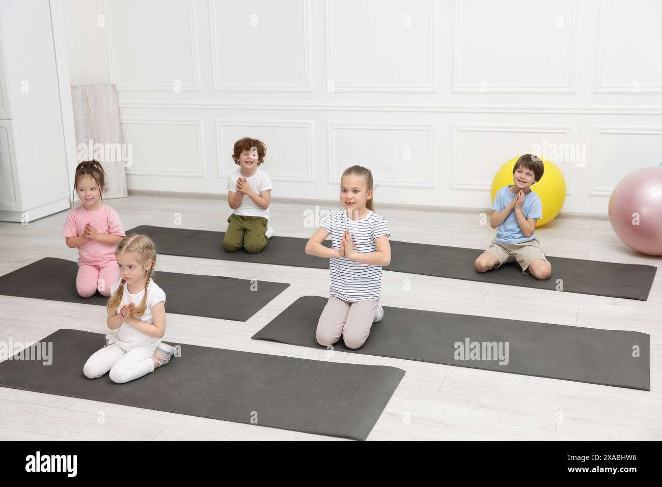 Groupe d'enfants faisant des exercices de gymnastique sur des tapis à l'intérieur Banque D'Images