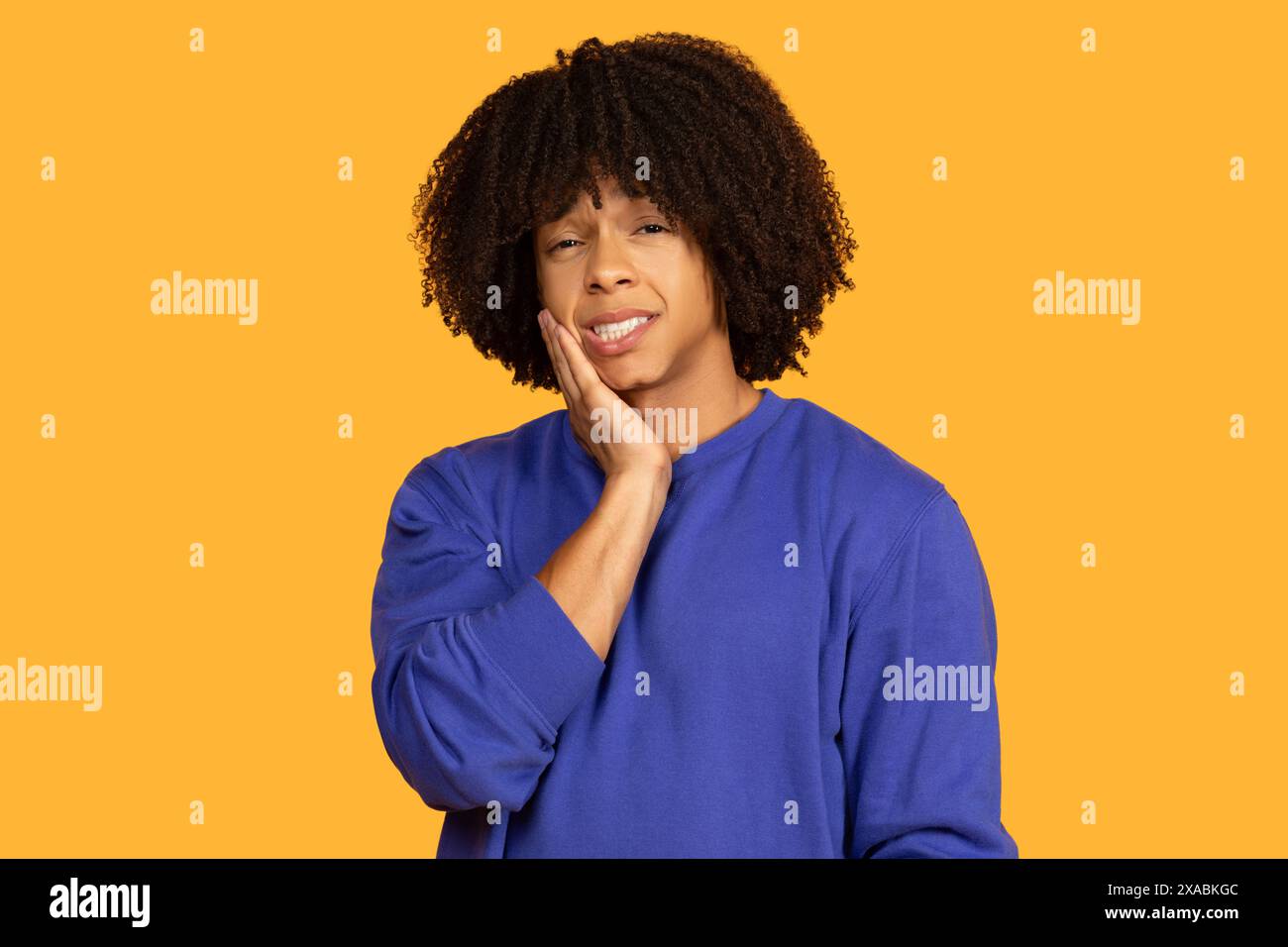 Jeune homme exprimant la douleur dentaire sur fond jaune solide Banque D'Images