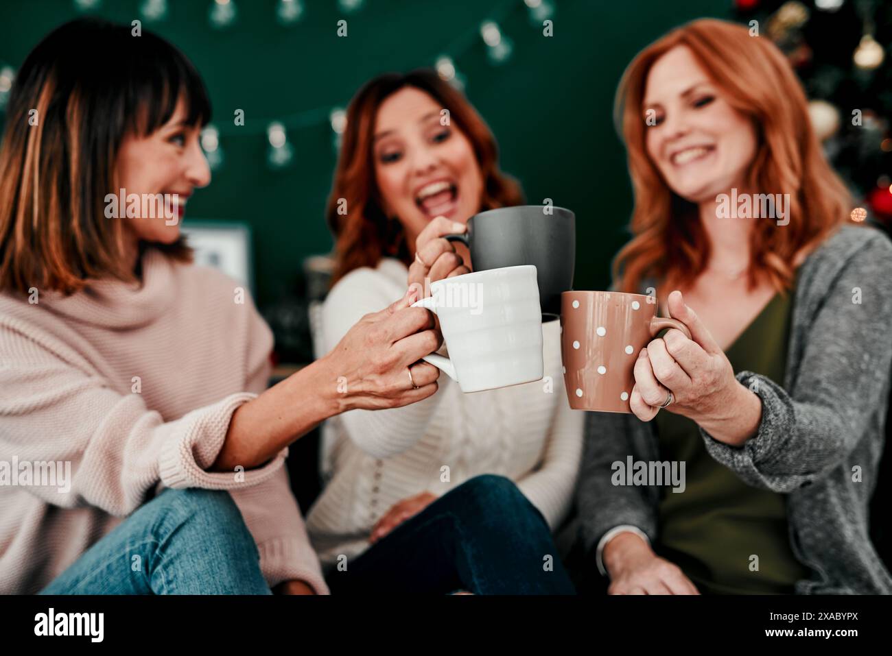 Noël, les femmes et les amis avec café, acclamations ou heureux en vacances de la saison des fêtes ou en groupe. Maison, salon ou personnes avec chocolat chaud, chaud ou Banque D'Images